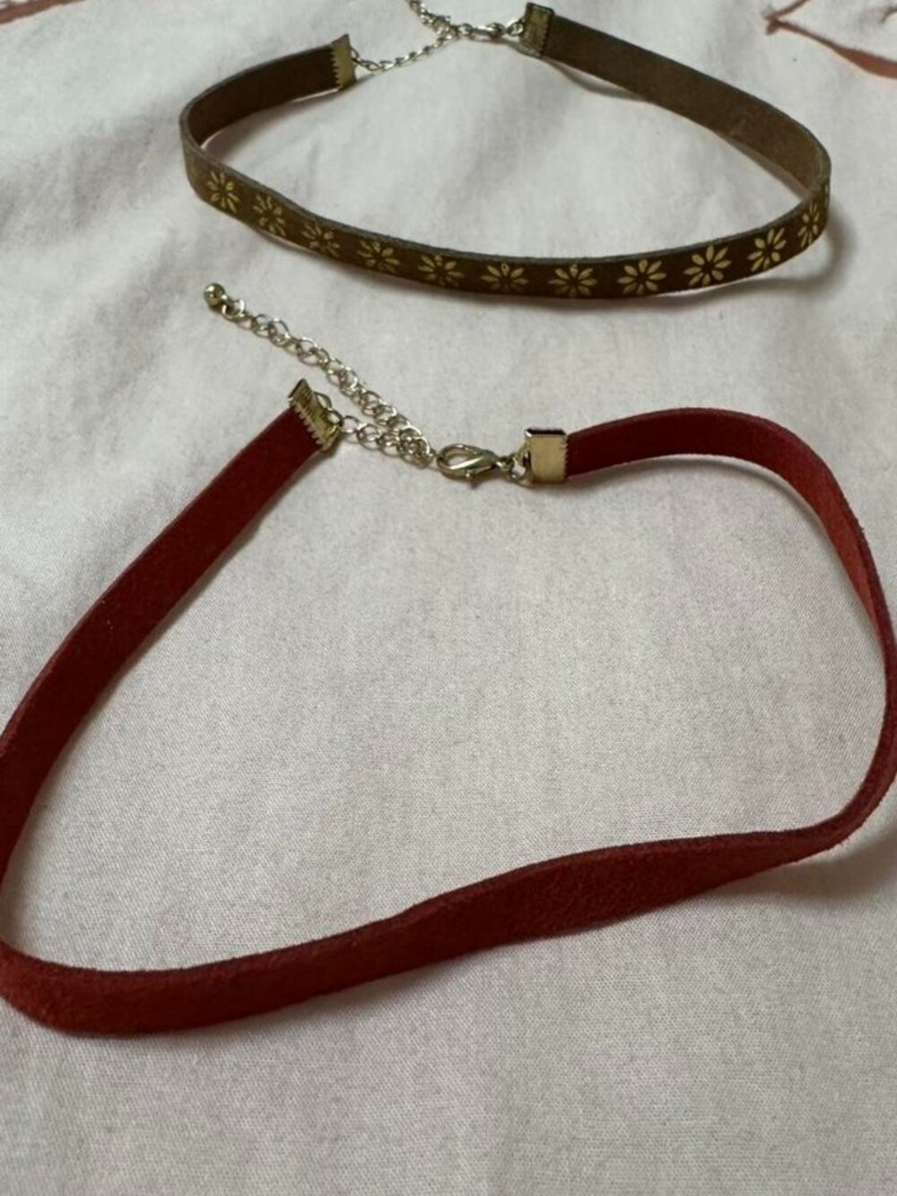Set of 2 adjustable suede look chokers with gold details.